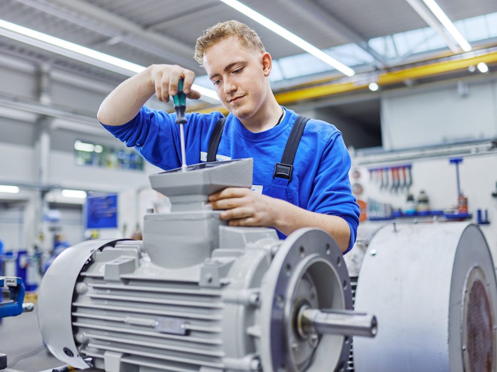 J. Schneider Elektrotechnik Azubi arbeitet mit einem Schraubenzieher an einem großen Elektromotor