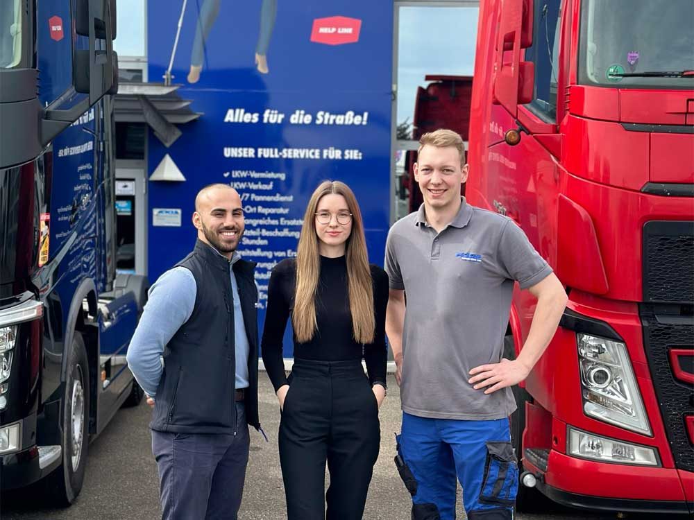 Auszubildende stehen zwischen zwei LKWs