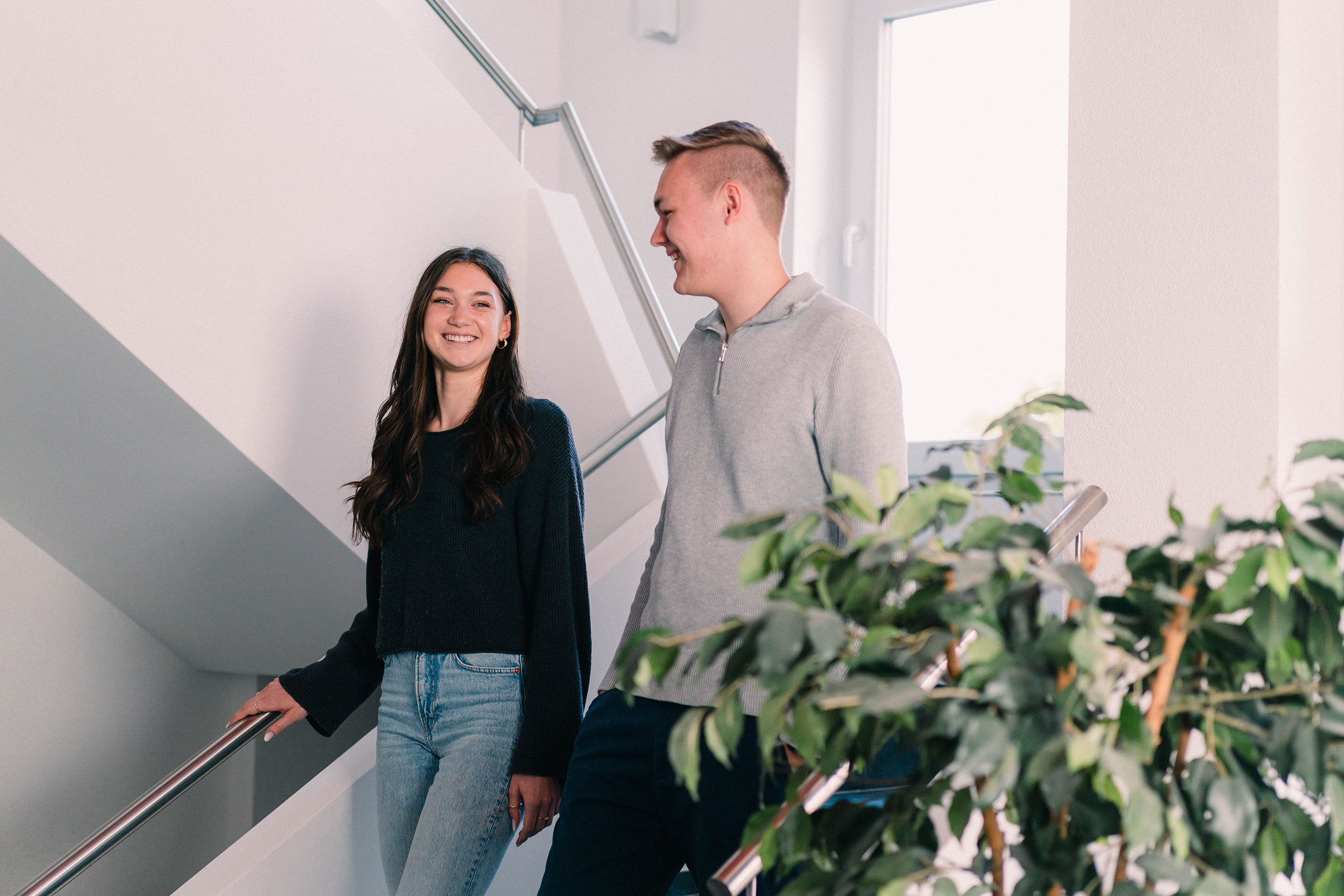 Eine junge Frau und ein junger Mann gehen eine Treppe hinunter und unterhalten sich